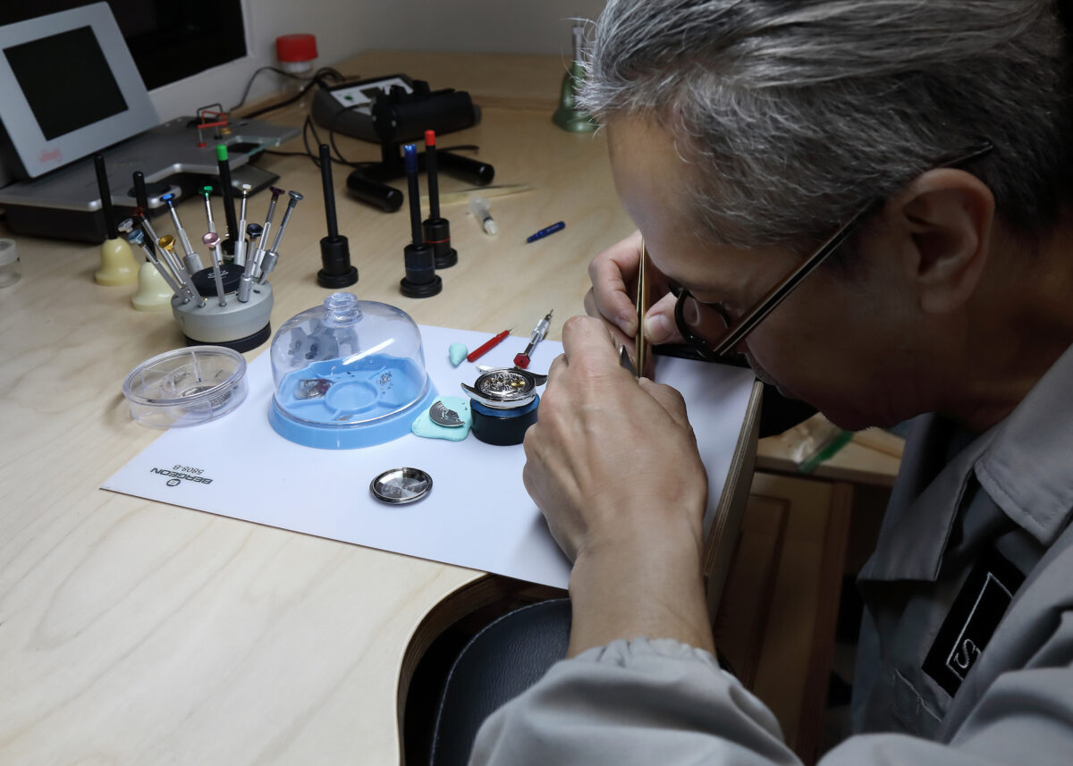 A professionally-trained watchmaker inspects a watch movement