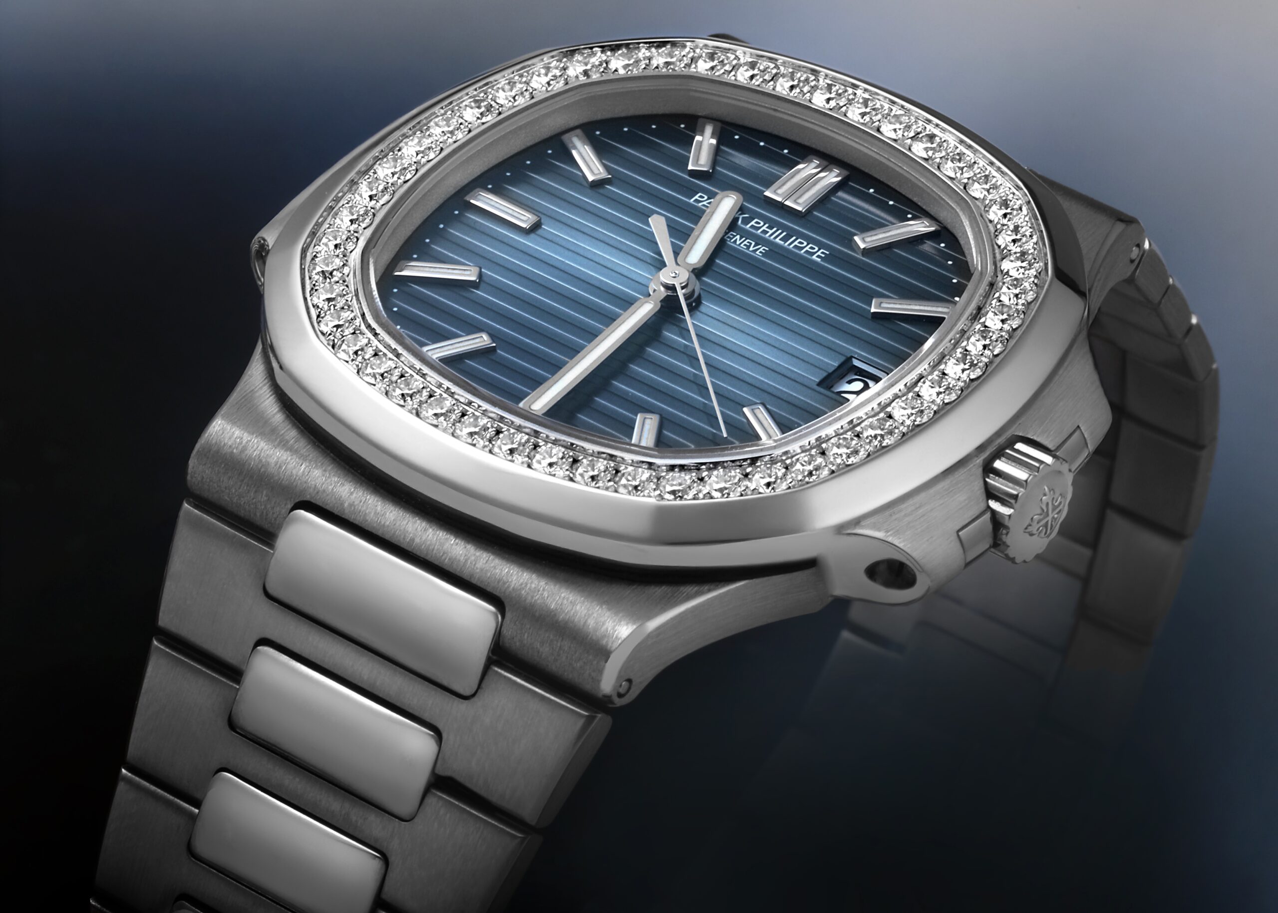 Patek Philippe Nautilus reference 5713/1G in 18k white gold featuring a factory diamond-set bezel and blue ribbed dial.