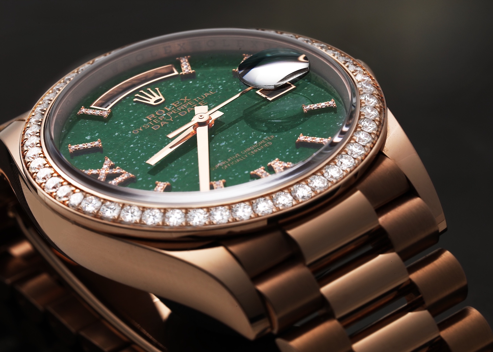 Close-up of a rose gold Rolex Day-Date 36 model 128345 watch, featuring a vibrant green aventurine dial with diamond hour markers, and a diamond-set bezel, on a President bracelet.