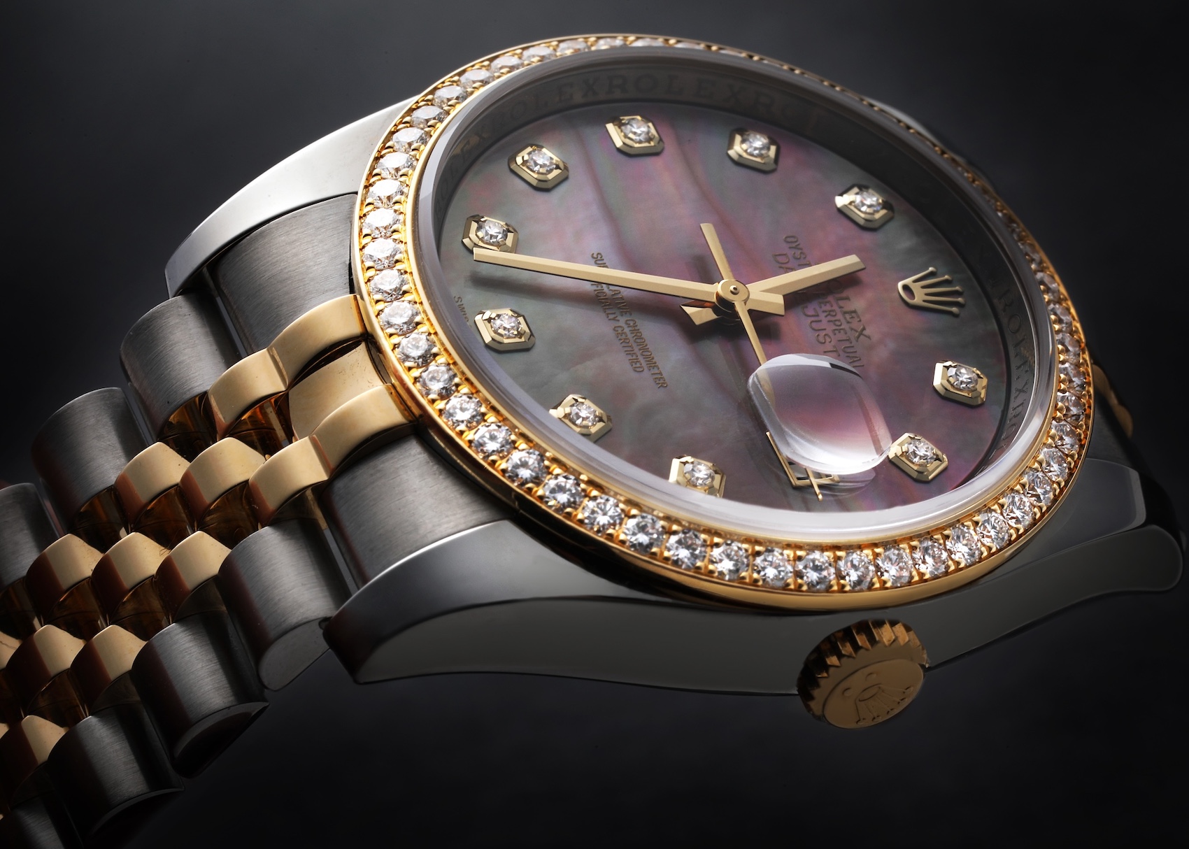 Close-up of a two-tone Rolex Datejust model 116243 watch, featuring a dark mother-of-pearl dial with diamond hour markers, and a diamond-set yellow gold bezel, paired with a Jubilee bracelet.