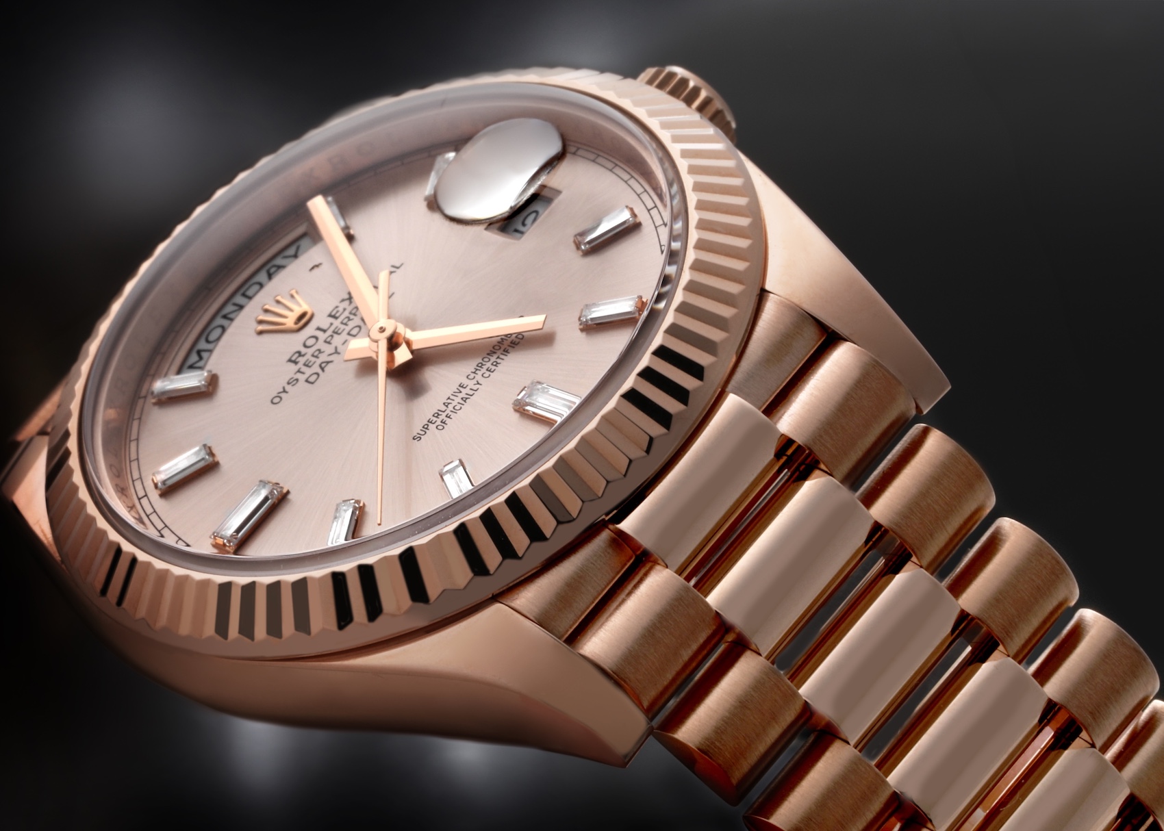 Close-up of a rose gold Rolex Day-Date 40 model 228235 watch, featuring a pink or champagne dial with baguette diamond hour markers, and a fluted bezel on a President bracelet.