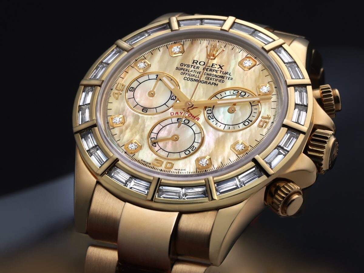 Close-up of a gold Rolex Daytona watch with a mother-of-pearl dial and diamond hour markers and baguette diamond bezel.