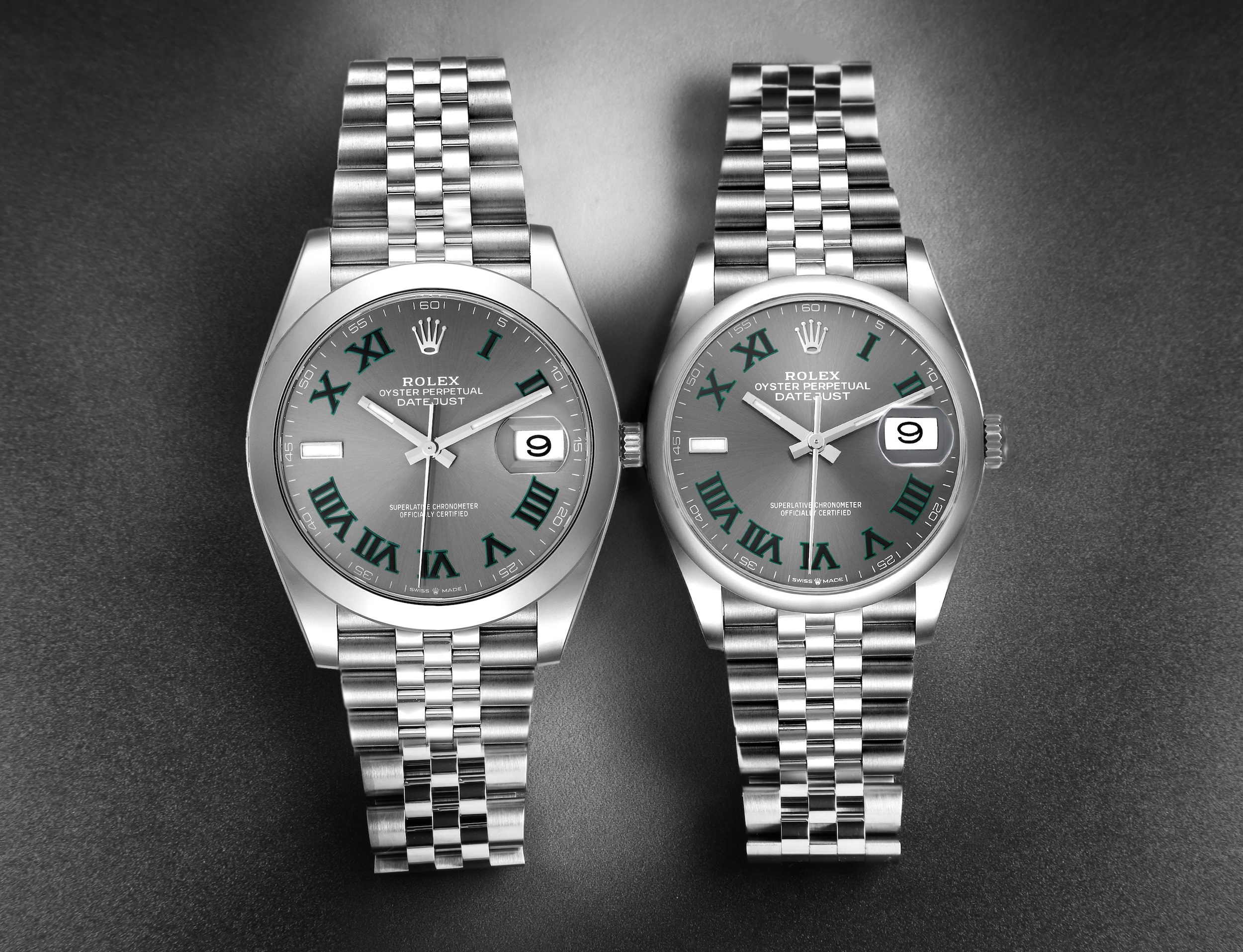Two Rolex Datejust 'Wimbledon' watches with slate grey dials and distinct green Roman numerals on Jubilee bracelets.