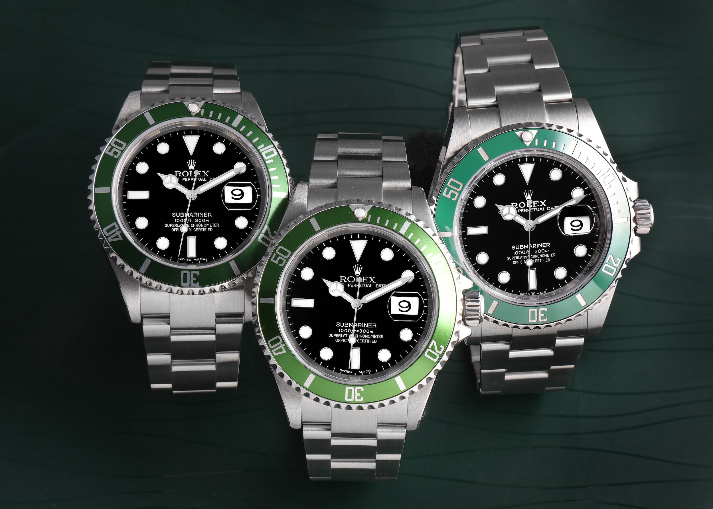 Three Rolex Submariner Date watches with green ceramic bezels and black dials, including the 'Kermit' and 'Starbucks' models.