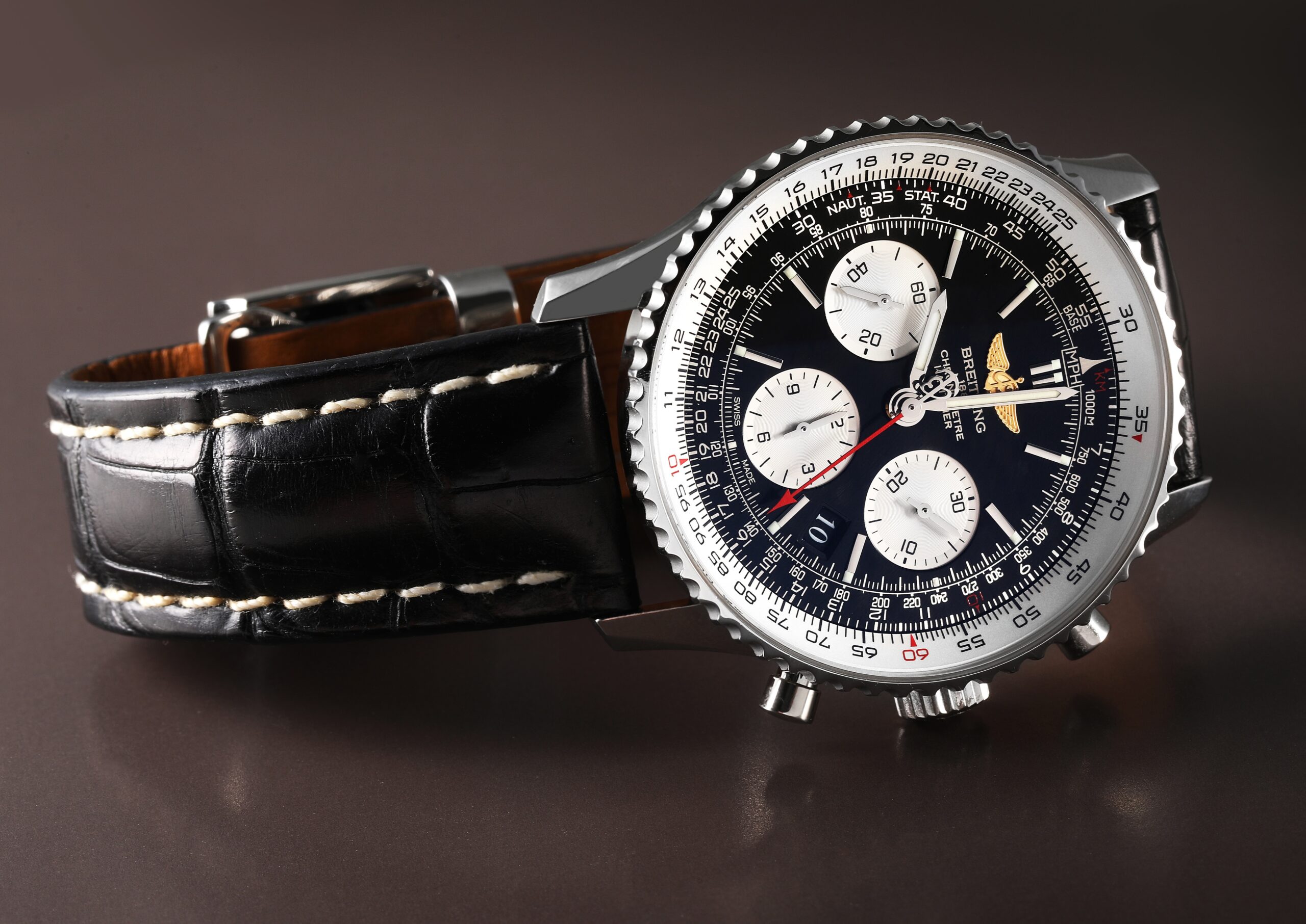 Angled shot of a Breitling Navitimer 01 watch, showcasing its intricate slide rule bezel and black dial with white chronograph sub-dials on a leather strap.