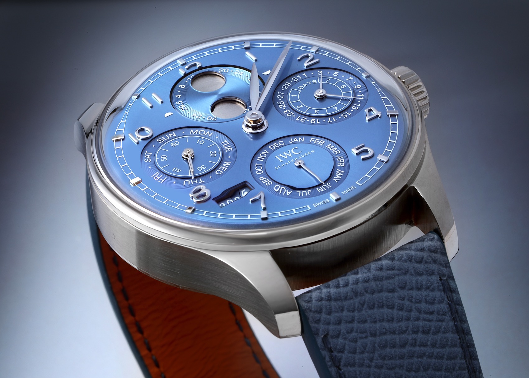 An IWC Portuguese Perpetual Calendar watch with a complex and beautiful blue dial showing the day, date, month, year, and moonphase complications.