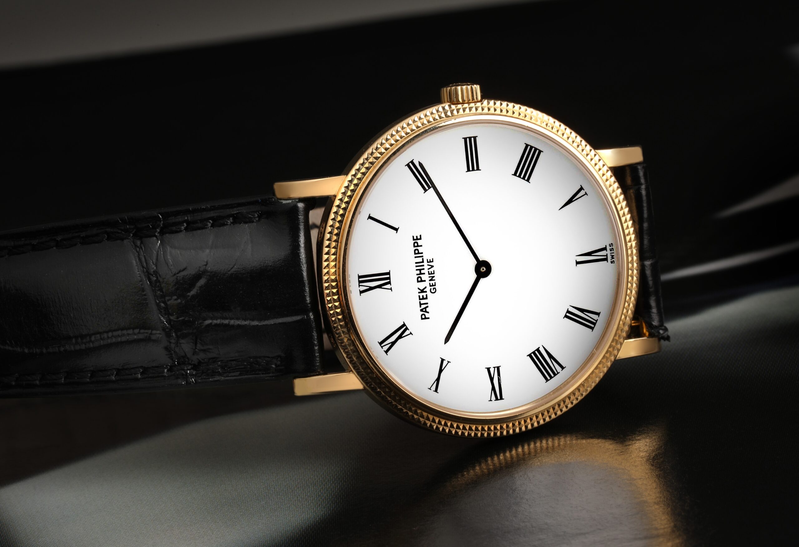 A classic Patek Philippe Calatrava 5120 in yellow gold, featuring its signature hobnail bezel and a clean white Roman numeral dial on a black leather strap.