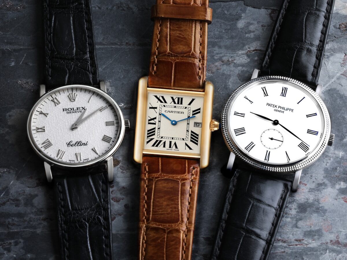 A trio of quintessential dress watches: a round Rolex Cellini with Roman numerals, a rectangular Cartier Tank, and a minimalist Patek Philippe Calatrava with a small seconds dial.