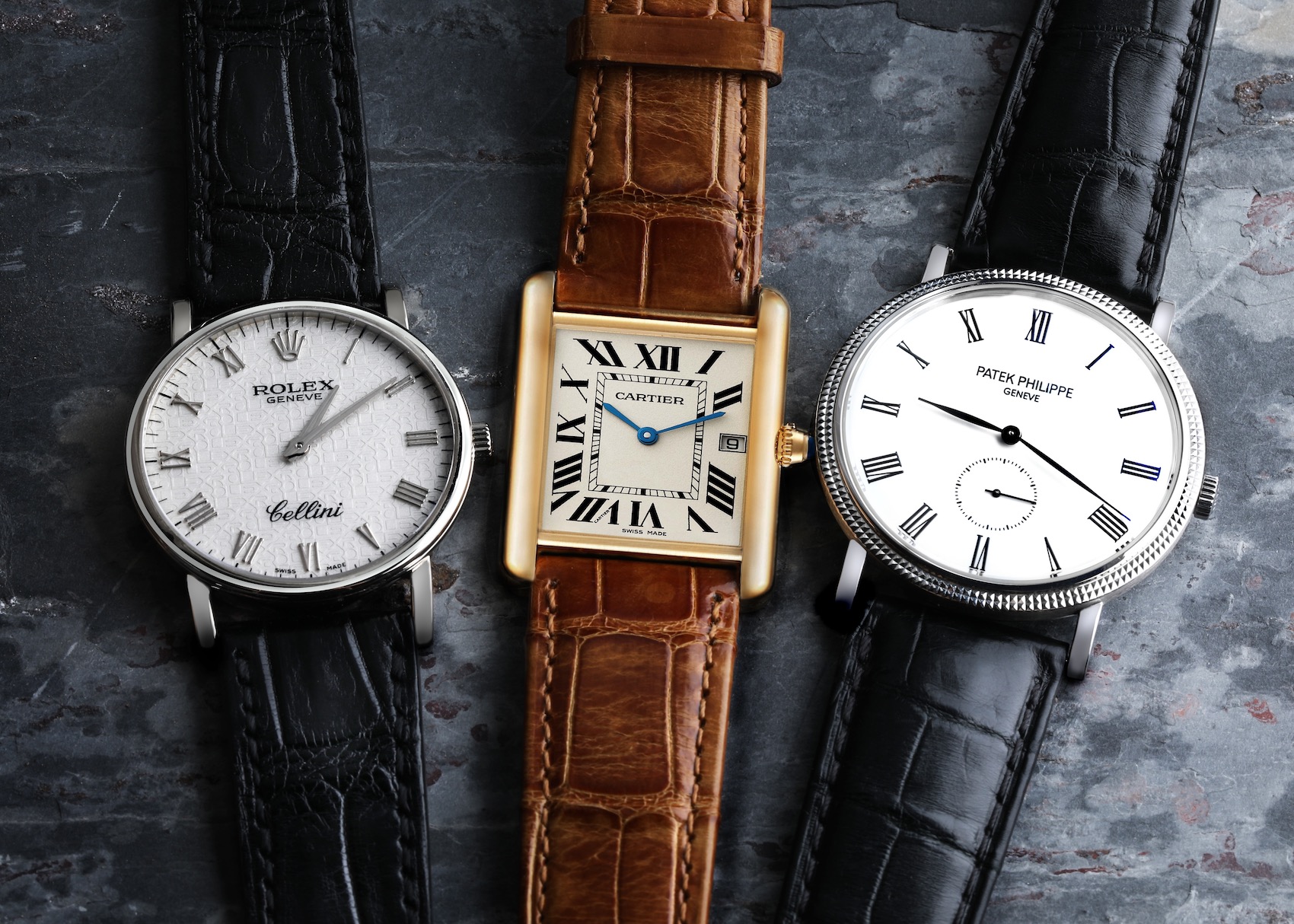 A trio of quintessential dress watches: a round Rolex Cellini with Roman numerals, a rectangular Cartier Tank, and a minimalist Patek Philippe Calatrava with a small seconds dial.