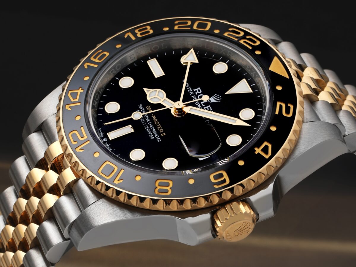 A detailed close-up of a two-tone Rolex GMT-Master II, showcasing its iconic black and grey bezel and the advanced Caliber 3285 movement that powers it.