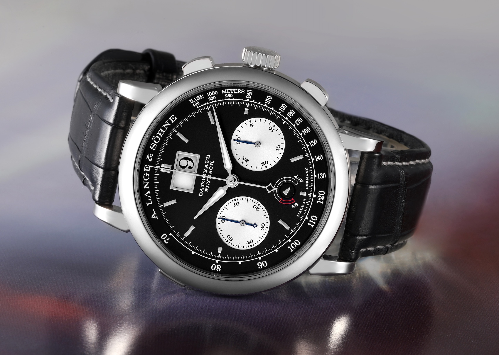 A close-up of the A. Lange & Söhne Datograph Up/Down watch, showing the intricate details of its black dial with silver subdials and the platinum case.