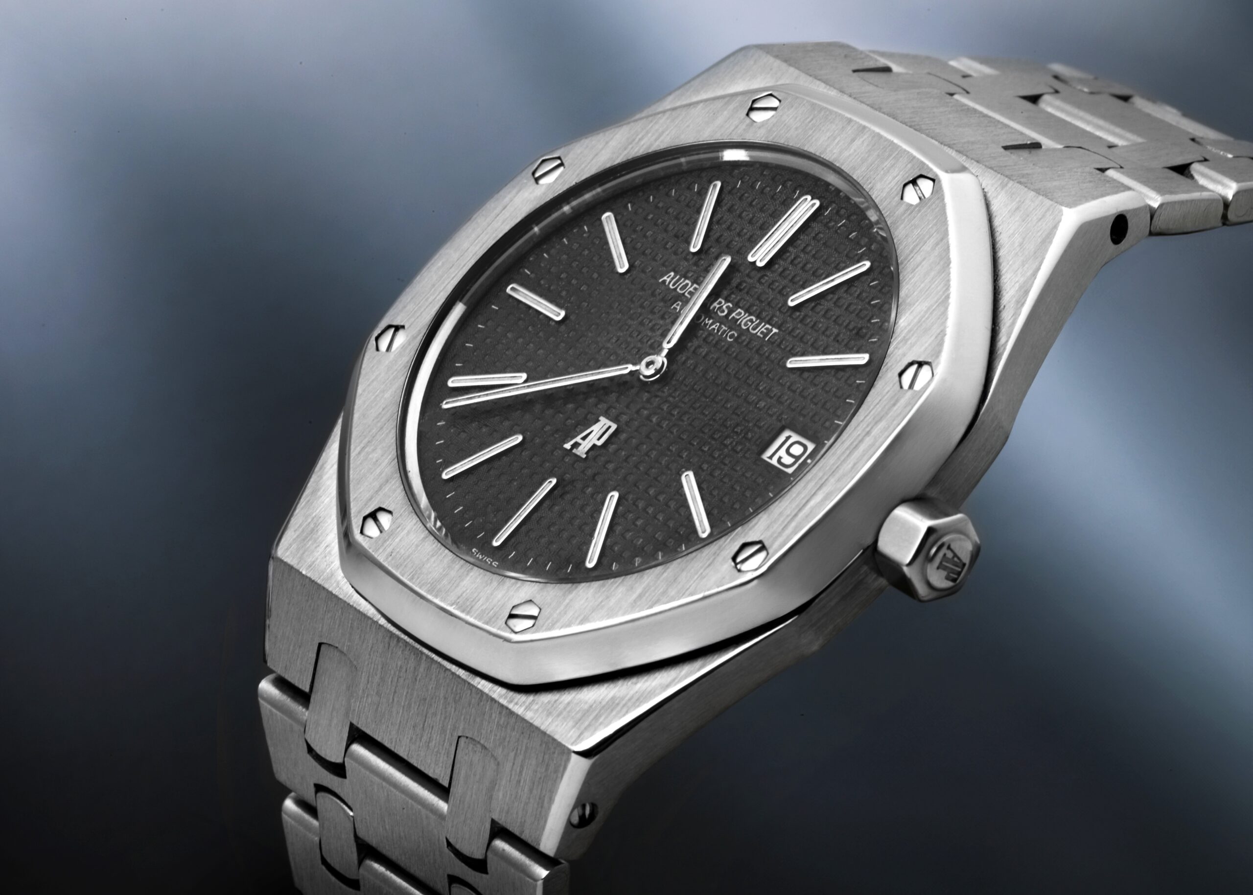 An Audemars Piguet Royal Oak men's watch featuring a stainless steel case and bracelet with a contrasting black waffle-patterned dial.