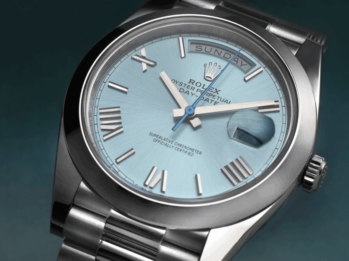A detailed macro shot of a prestigious platinum Rolex Day-Date with an ice blue dial, clearly displaying the "IIII" for the number four.