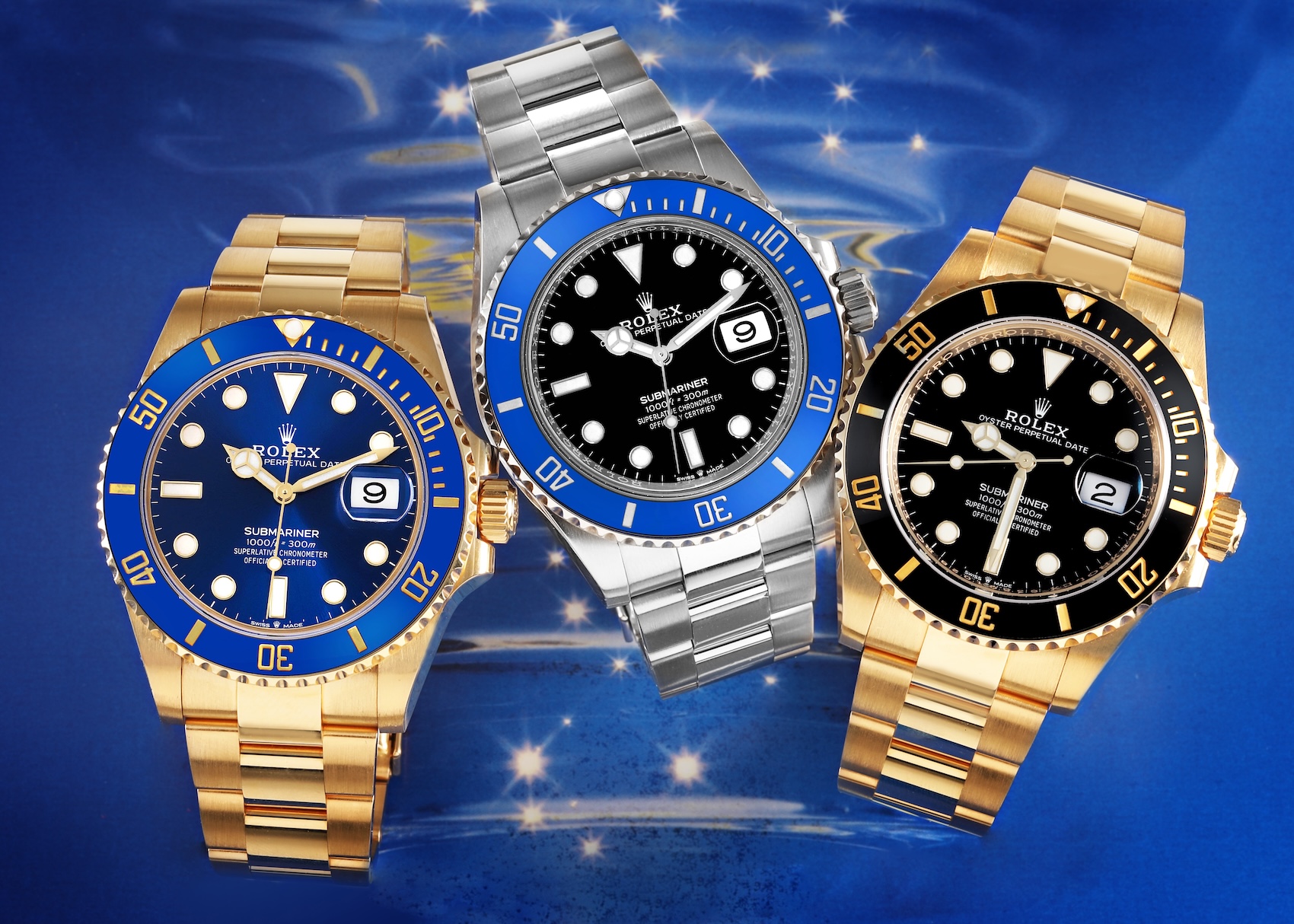 Three Rolex Submariner Date watches in precious metals. From left to right: a yellow gold model with a blue dial and bezel, a white gold model with a blue bezel and black dial, and a yellow gold model with a black dial and bezel.