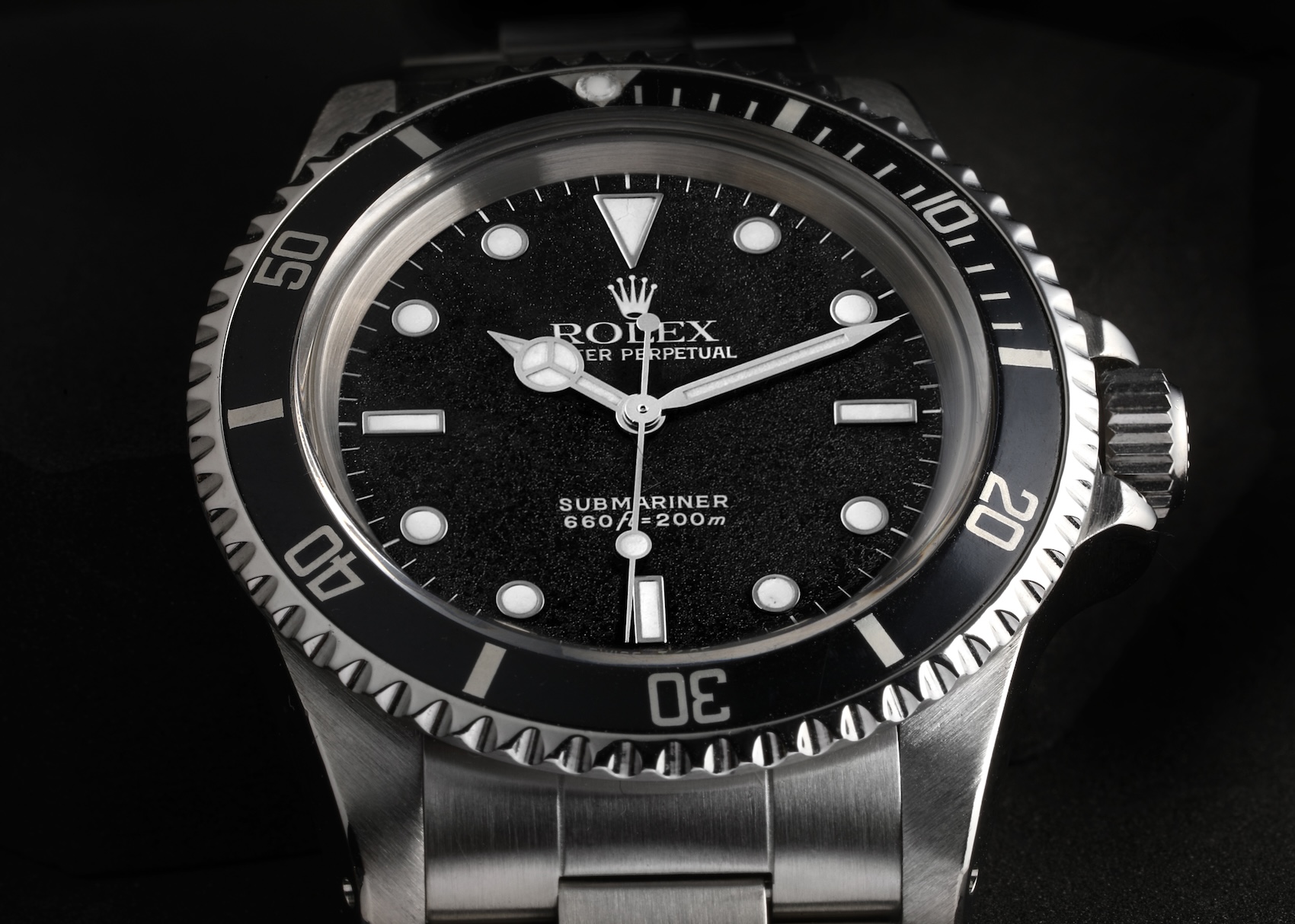 A close-up of a vintage Rolex Submariner reference 5513. It features a black "frosted" dial, no date window, white hour markers, and a stainless steel case with a black unidirectional bezel.