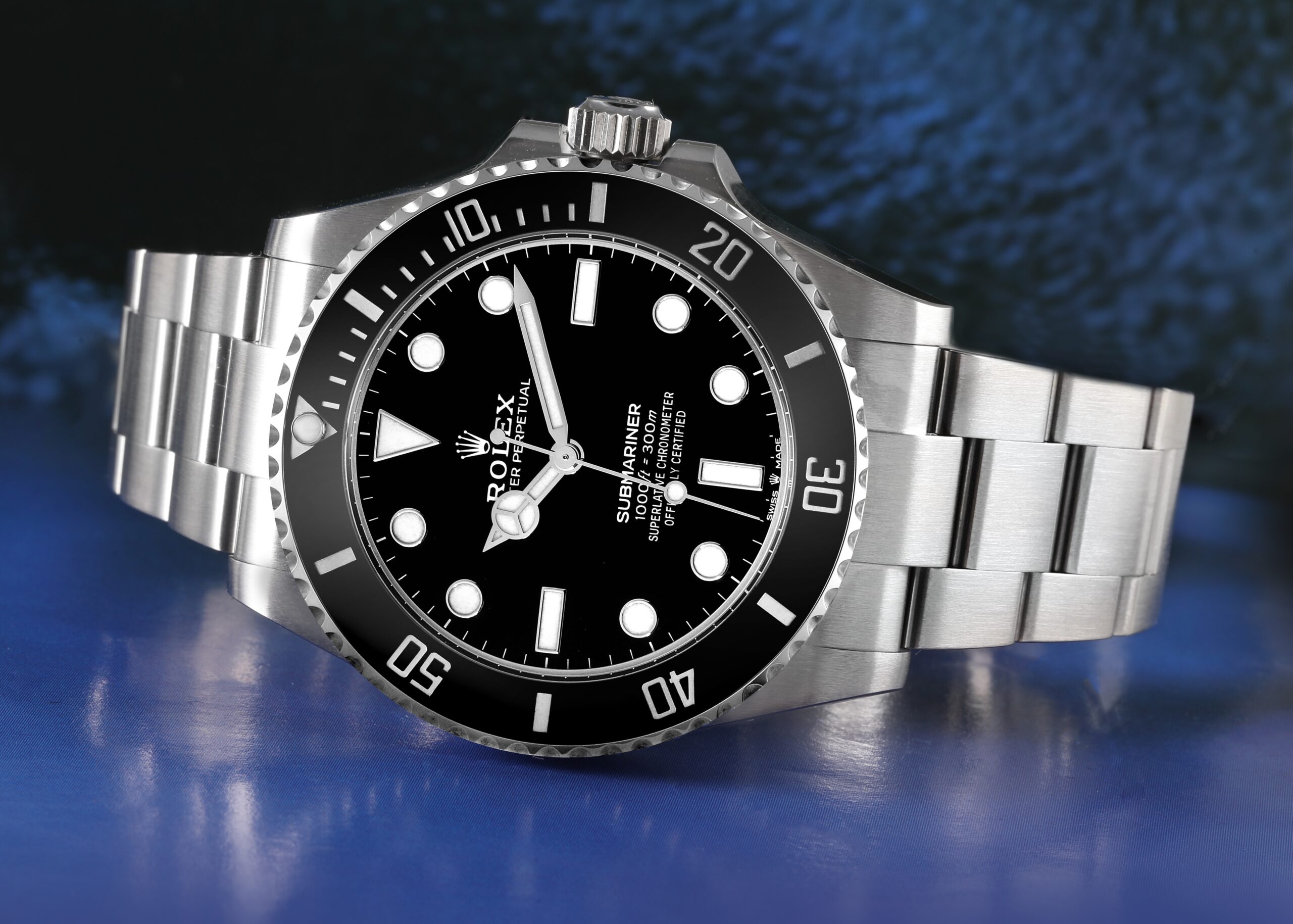Close-up of a stainless steel Rolex Submariner watch with a black dial, luminous hour markers, and a black rotating dive bezel.