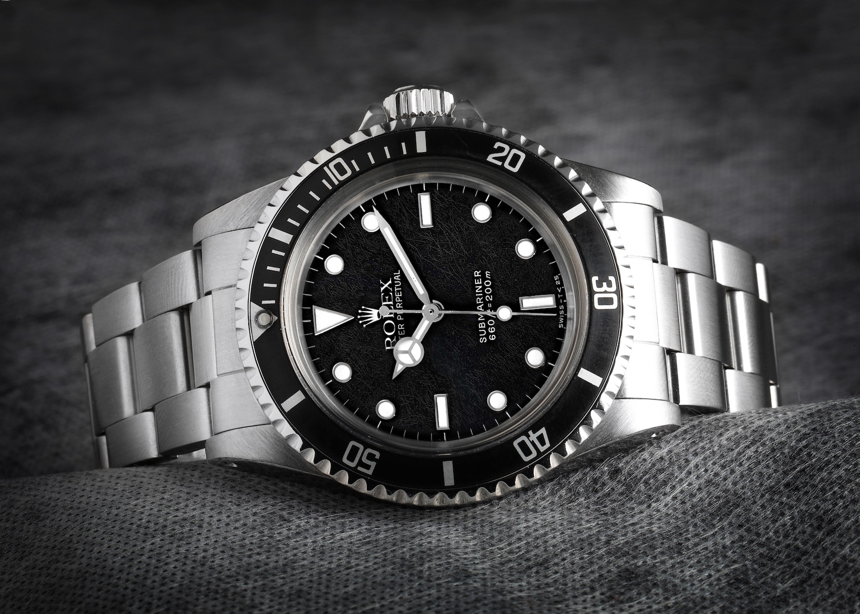 A close-up of a vintage Rolex Submariner Spider Dial 5513 men's watch in stainless steel, showcasing its unique "spider web" cracked black dial.