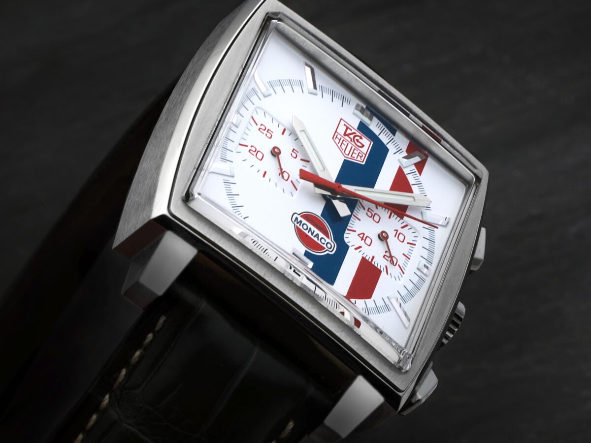 A close-up of the TAG Heuer Monaco CW2118, the "McQueen" limited edition, showing its white dial with iconic red and blue racing stripes.