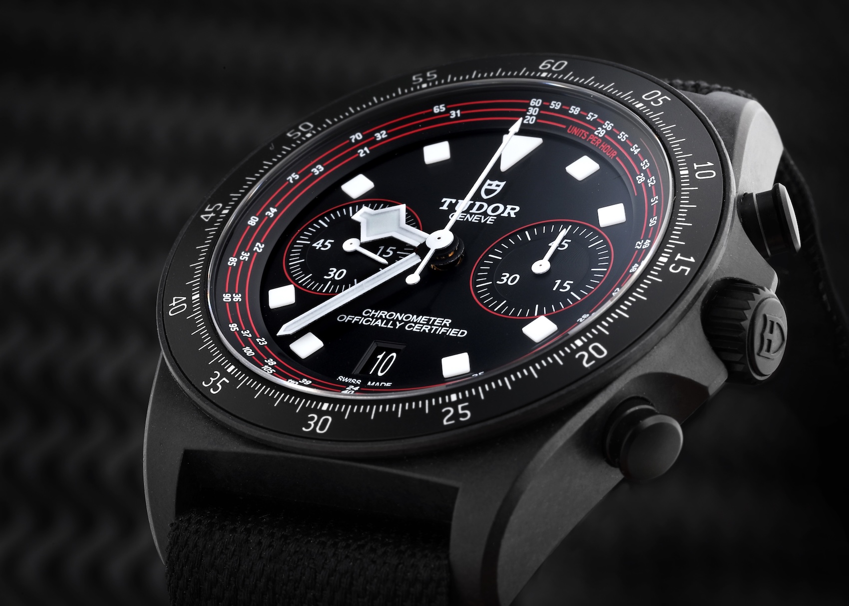 A close-up side profile of the Tudor Pelagos FXD Chrono Cycling Edition, highlighting the matte finish of the carbon case, the prominent winding crown, and the black fabric strap.