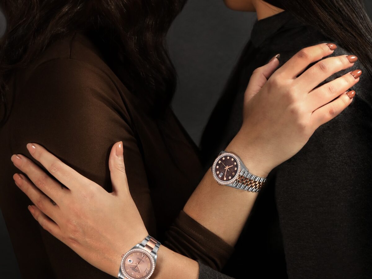 Two women elegantly display their luxury watches, one with a two-tone case and chocolate diamond dial, the other with a steel case and pink diamond dial, for a blog post on the best watches for women.