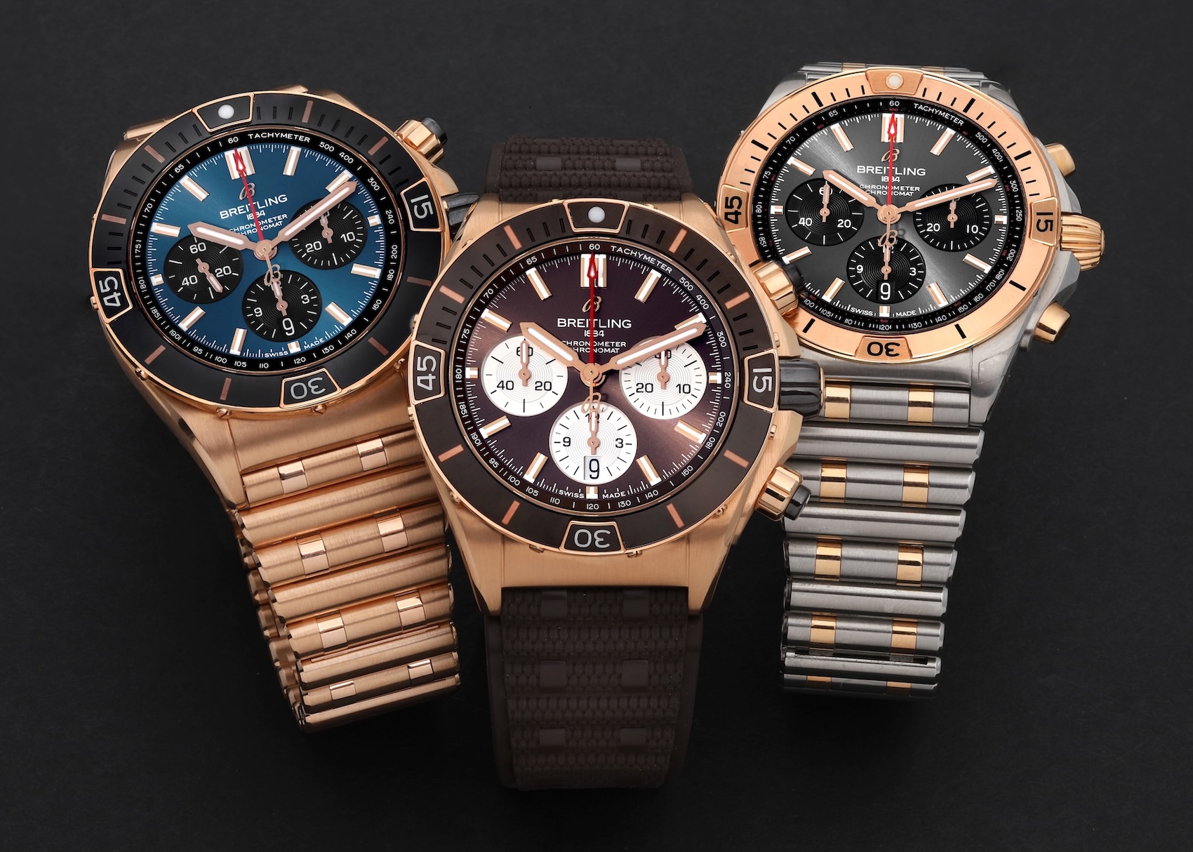 Three Breitling Chronomat watches displayed side-by-side, showcasing different case materials including full rose gold, and two-tone steel and gold, with various dial colors and strap options.