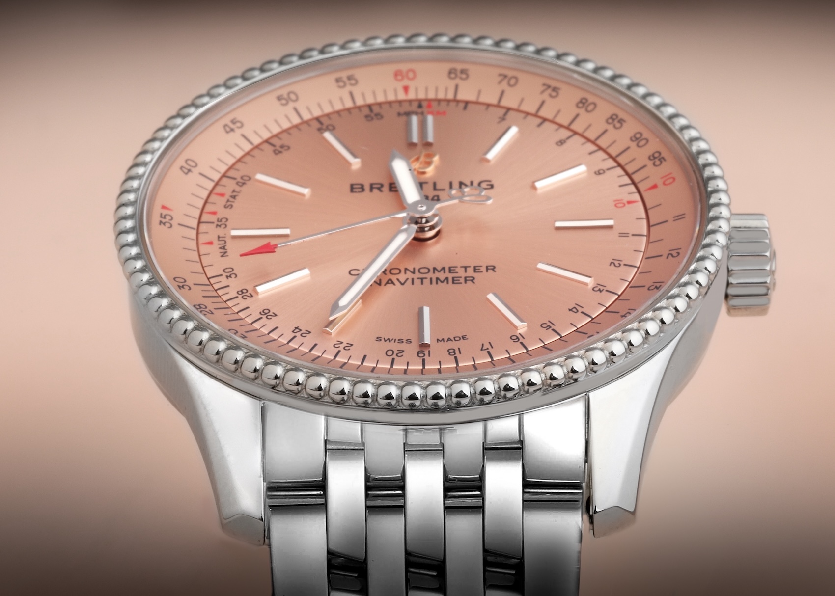 A close-up of a Breitling Navitimer Automatic 35 watch with a metallic salmon-pink dial and signature beaded bezel.