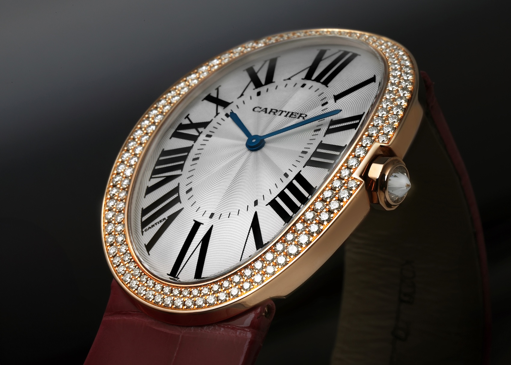 The Cartier Baignoire XL WB520005 watch, shown at an angle, with its 18k yellow gold oval case, diamond-set bezel, and silvered dial on a red alligator strap.