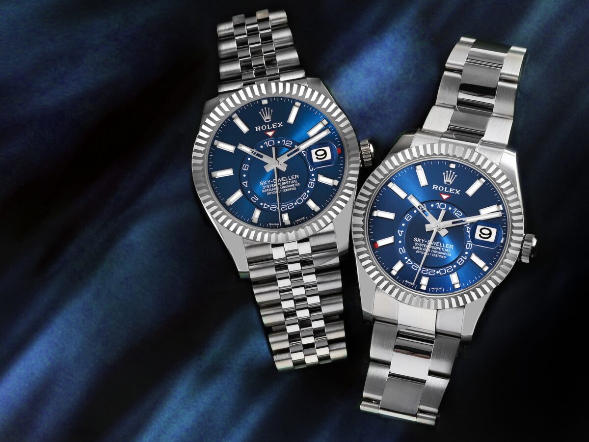 Two stainless steel Rolex Sky-Dweller watches with vibrant blue dials laid side-by-side, one featuring a sporty Oyster bracelet and the other a more formal Jubilee bracelet.