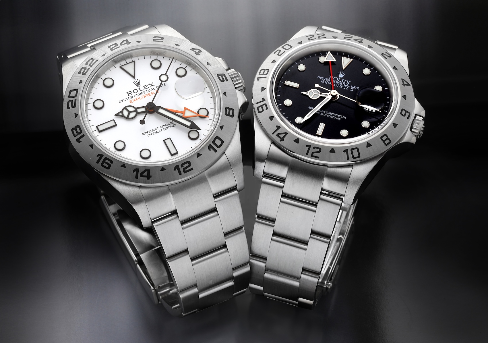Two Rolex Explorer II models side-by-side, comparing the modern white "Polar" dial reference 216570 with its smaller predecessor, the black dial 16570.
