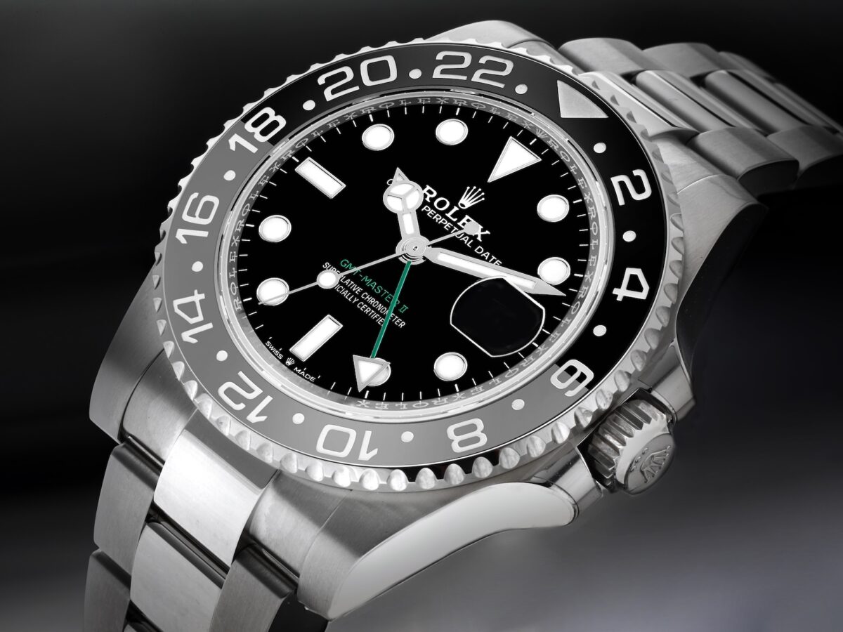 A close-up of the stainless steel Rolex GMT-Master II 126710GRNR on an Oyster bracelet, focusing on the black dial, green GMT hand, and black and grey bezel.