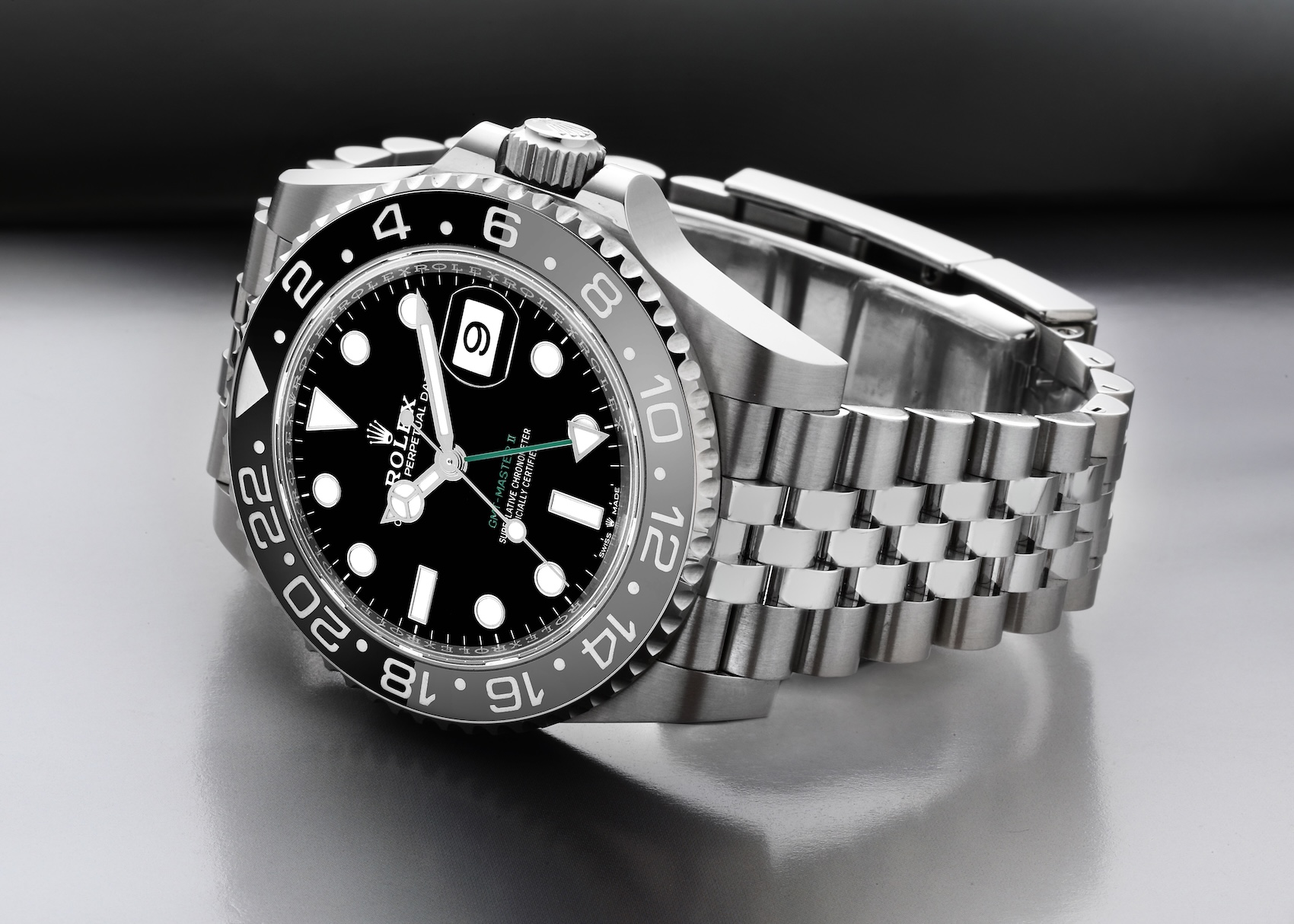 An angled view of the stainless steel Rolex GMT-Master II 126710GRNR, featuring the black and grey Cerachrom bezel, a black dial with a green GMT hand, and a five-link Jubilee bracelet.
