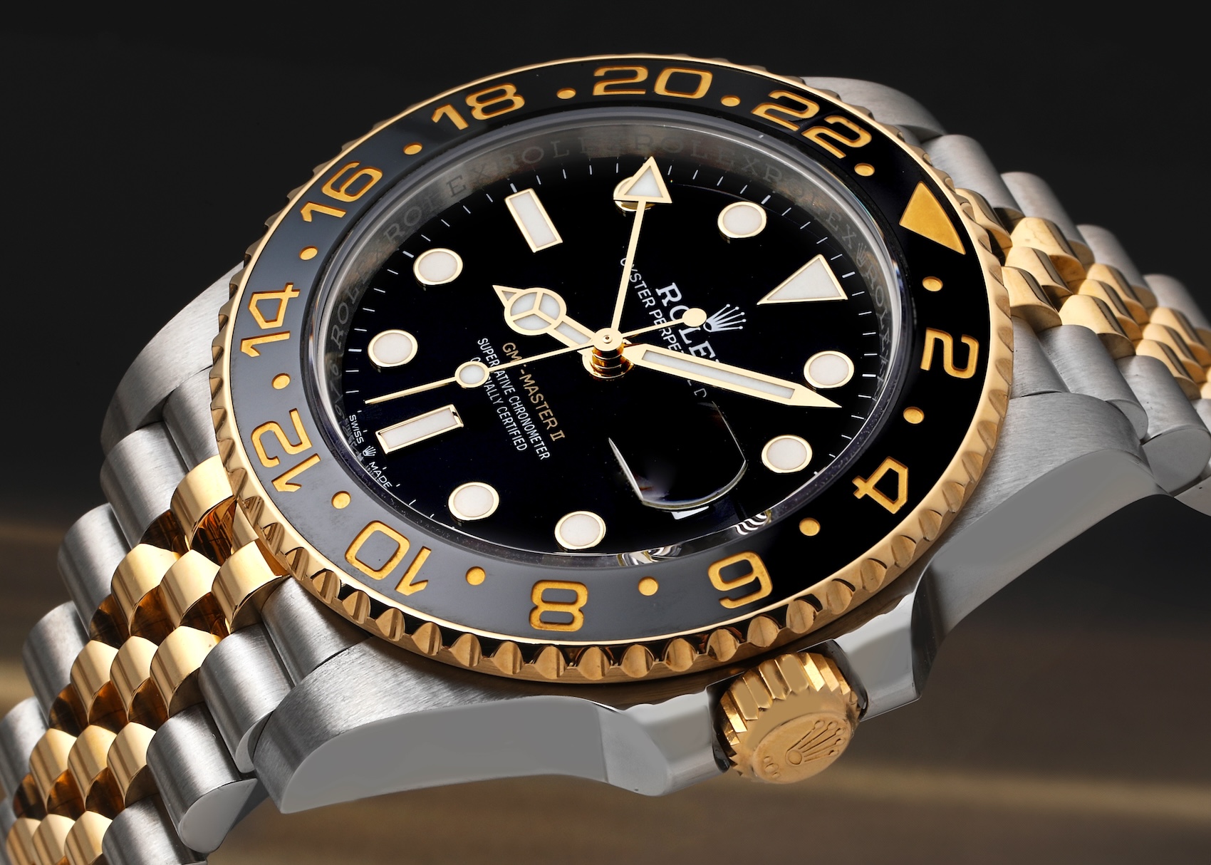 A detailed shot of the two-tone Yellow Rolesor Rolex GMT-Master II 126713GRNR, showing the black and grey bezel, black dial, and steel and yellow gold Jubilee bracelet.