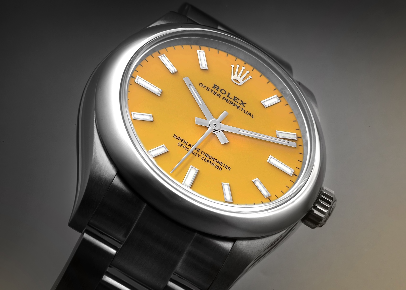 A macro shot of a Rolex Oyster Perpetual featuring a bold, lacquer yellow dial and stainless steel case.