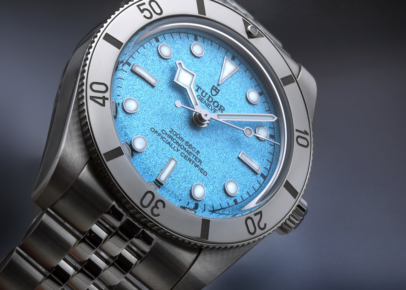 An angled beauty shot of the Tudor Black Bay 54, focusing on the frosted texture of the Lagoon Blue dial, the luminescent hour markers, and the signature snowflake hands.