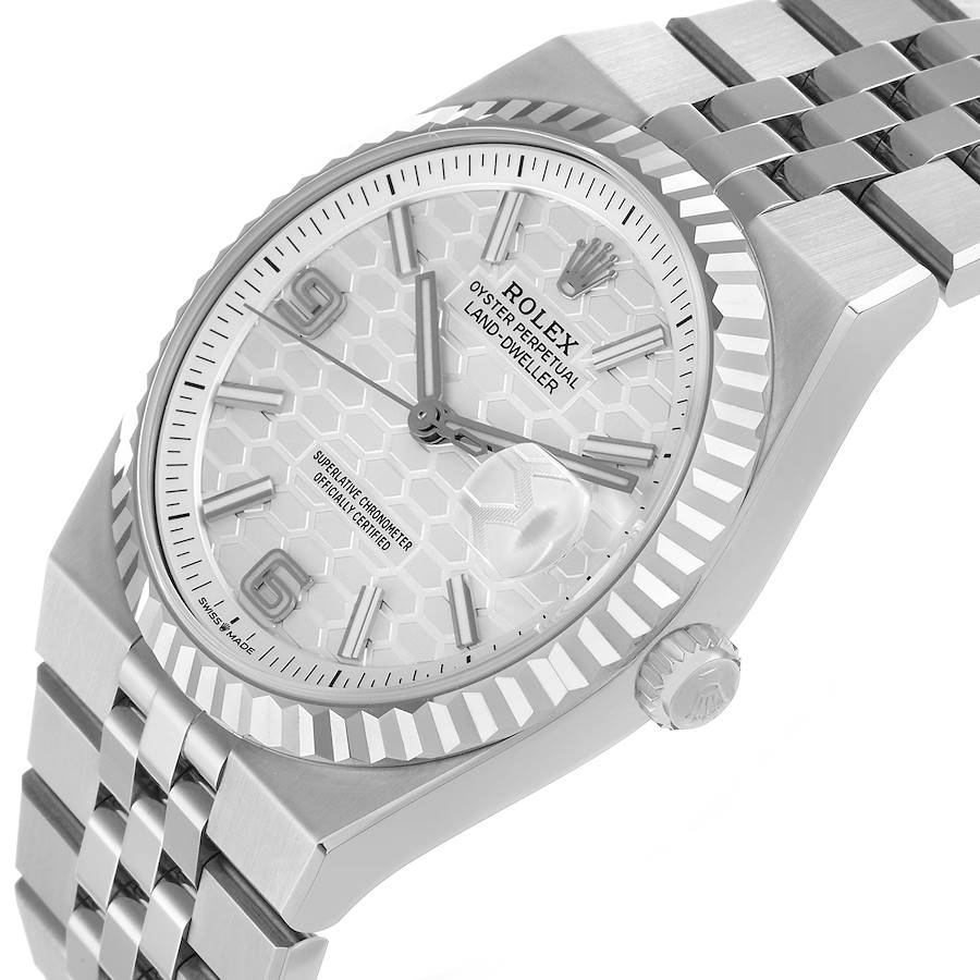 An angled shot of the Rolex Land-Dweller watch on a clean white background. The image clearly shows the white honeycomb dial, the Cyclops lens over the date at 3 o'clock, and the five-piece link Jubilee bracelet.