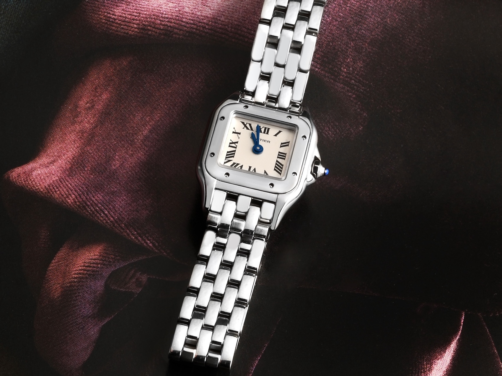A Cartier Panthere midsize steel watch (WSPN0007) laid flat, showing its square case, classic Roman numeral dial, and highly flexible, brick-like bracelet.