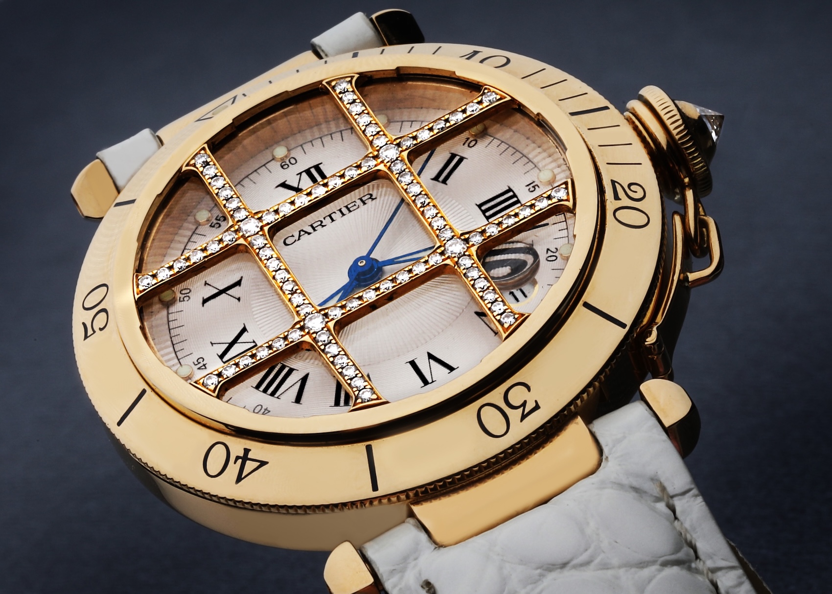 Close-up of a Cartier Pasha 38mm watch in yellow gold. A distinctive, removable diamond-set grid, or 'grille,' is placed over the silver dial, which features Roman numerals.