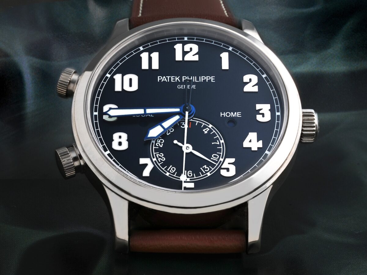 A head-on dial shot of the Patek Philippe Calatrava Pilot Travel Time 5524G, featuring a legible blue dial, large white gold numerals, and a brown leather strap.