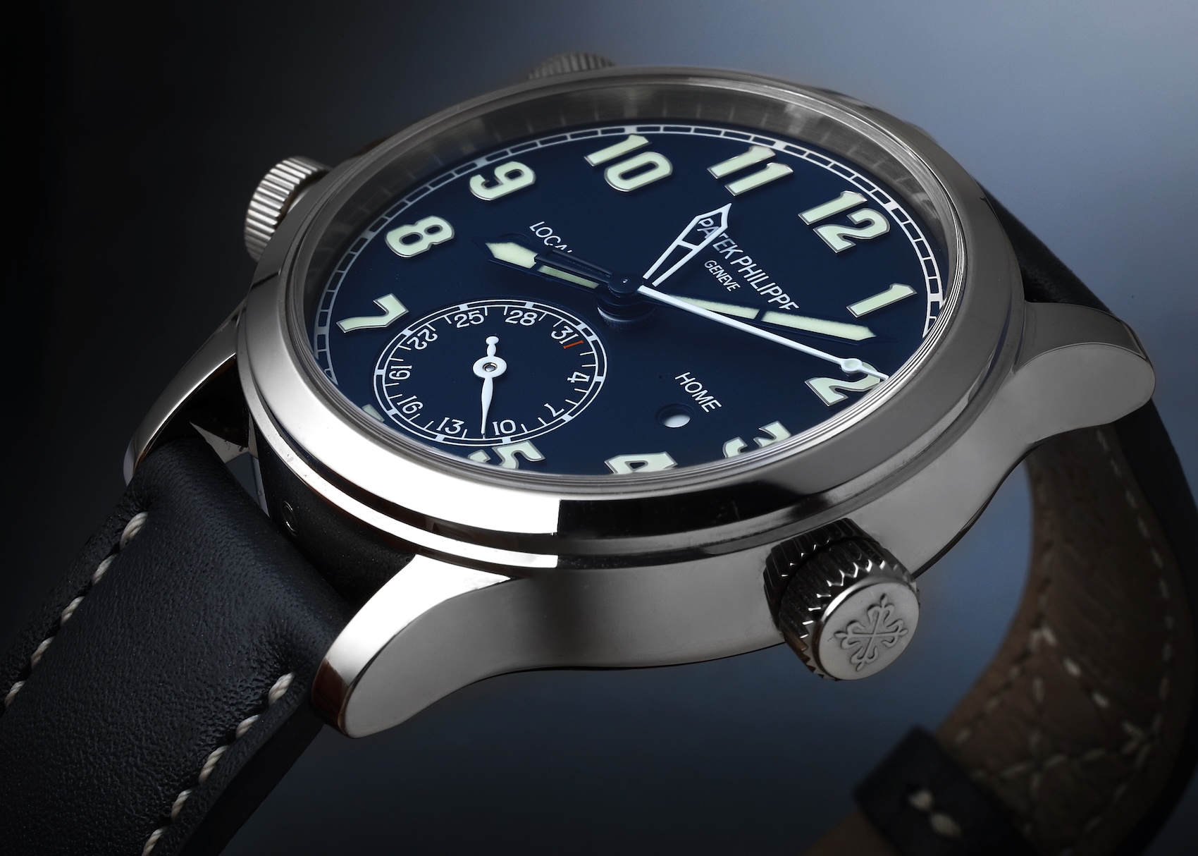 An angled profile shot of the Patek Philippe Calatrava Pilot Travel Time 5524G in white gold, showing its blue dial, luminous hands, and side pushers.