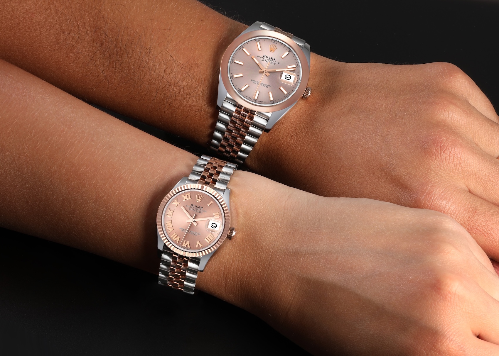 A "His and Hers" set of two-tone Rolex Datejust watches, showing a larger model on an Oyster bracelet and a smaller model on a Jubilee bracelet, both in Steel and Everose gold with matching pink dials.