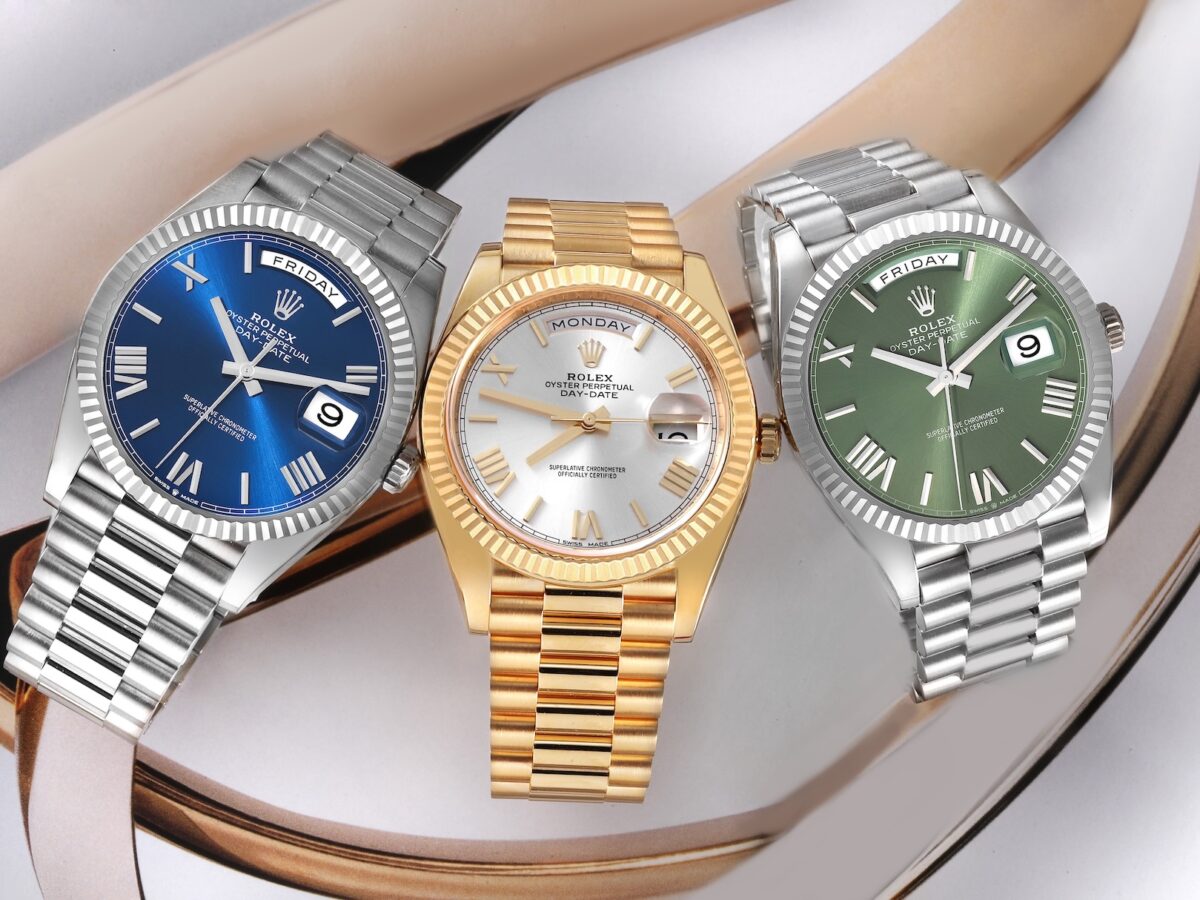 A trio of Rolex Day-Date 40 watches in platinum, yellow gold, and white gold, showcasing blue, silver, and olive green dials with Roman numerals.