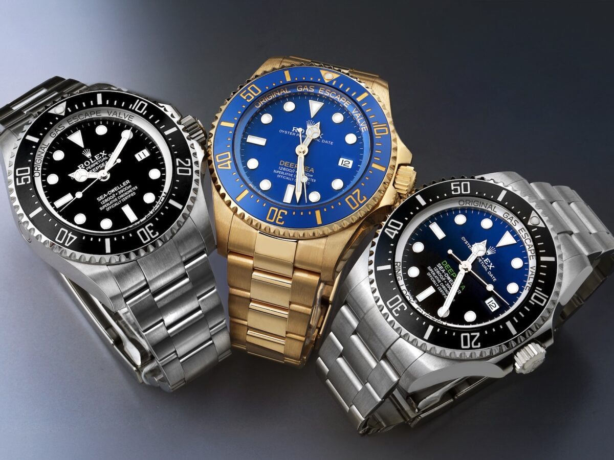 Three Rolex Deepsea watches arranged together: The steel Black Dial, the 18k Yellow Gold Ref. 136668, and the steel D-Blue "James Cameron" edition.