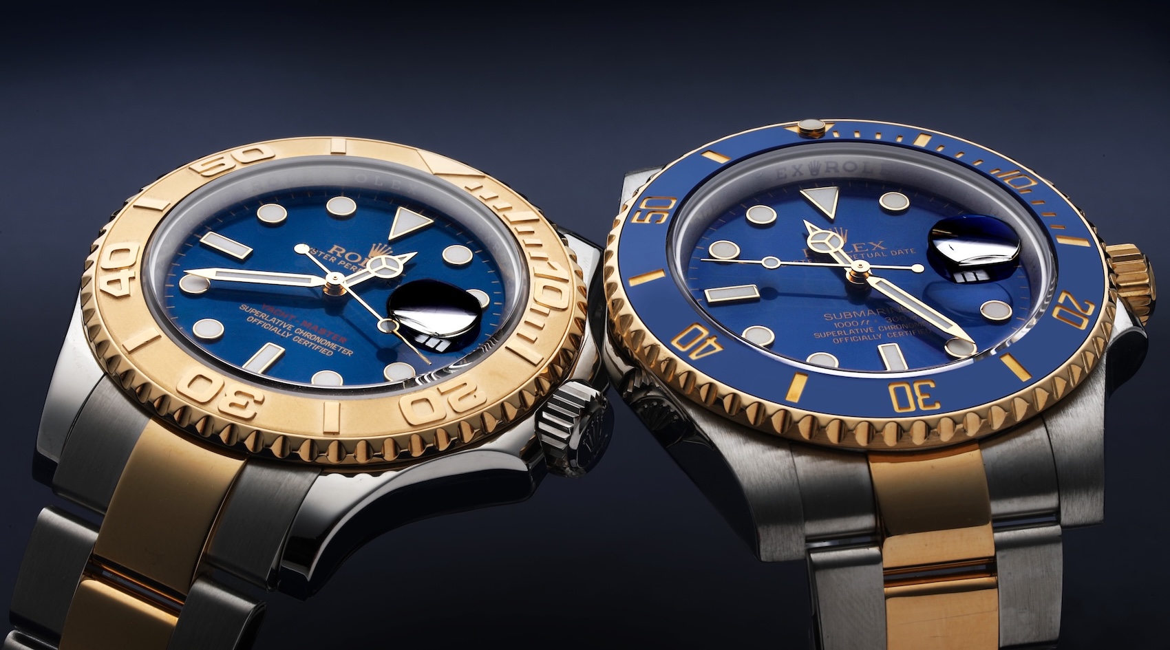  Two two-tone Rolex watches, a Yacht-Master with a gold bezel and a Submariner with a blue bezel, are displayed side-by-side, both featuring striking blue dials.