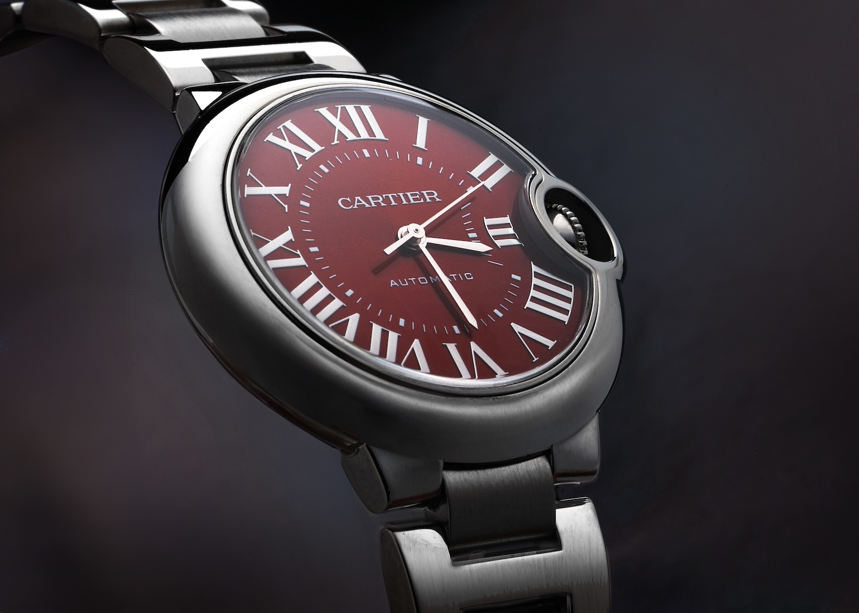 Close-up of the Cartier Ballon Bleu 33mm in stainless steel featuring a deep red sunray dial and Roman numerals (Ref. WSBB0052).