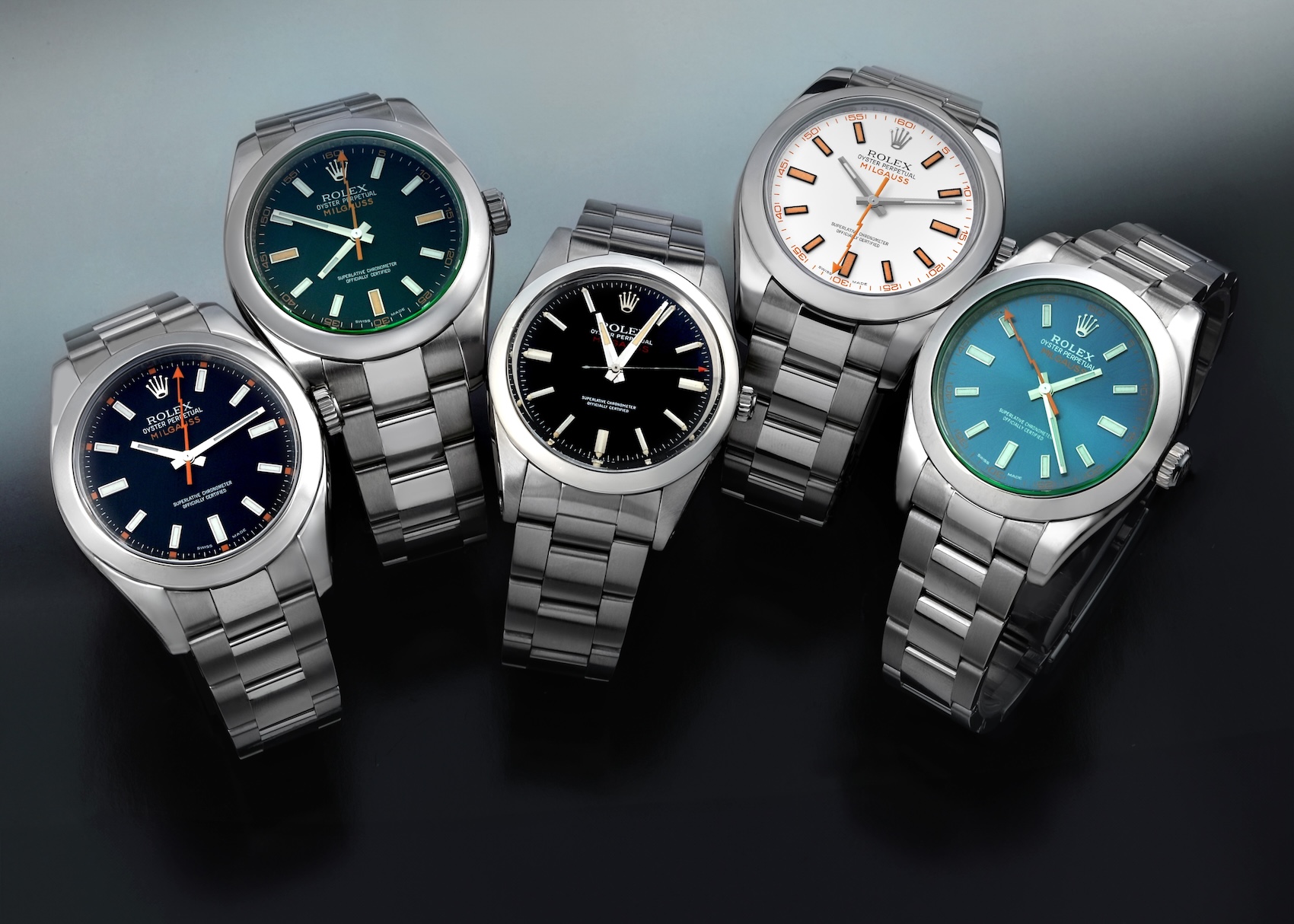 A collection of five Rolex Milgauss models including the vintage ref 1019, modern 116400 white and black dials, and 116400GV Z-Blue and black dials.