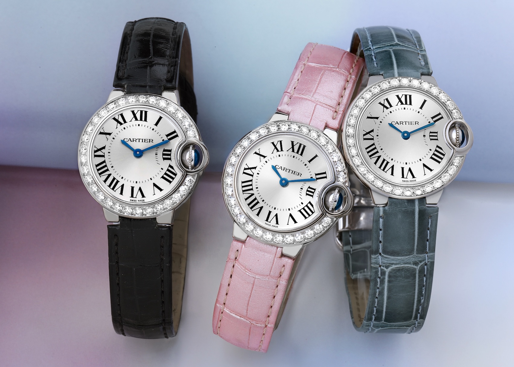 Three Cartier Ballon Bleu 28mm white gold watches with diamond bezels, shown with black, pink, and grey leather straps.