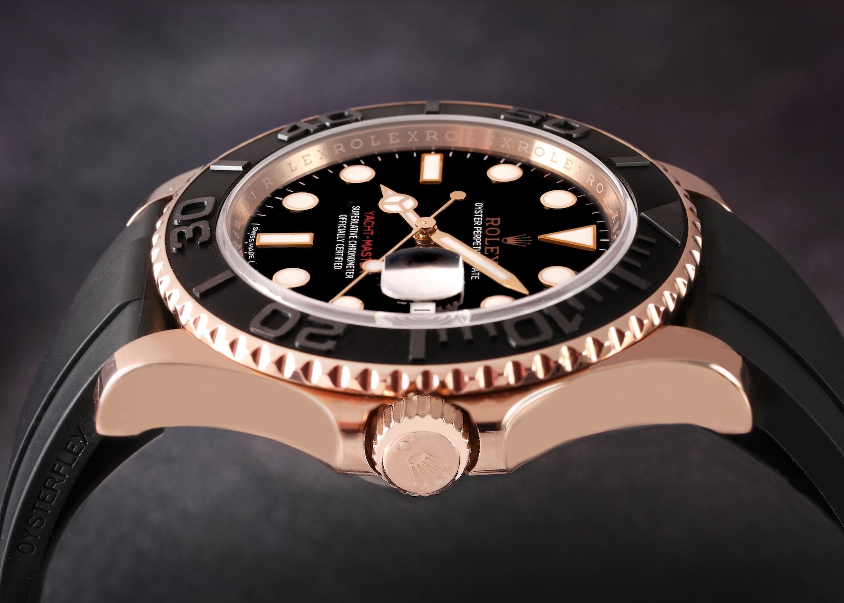 Side profile of a Rolex Yacht-Master 40 in 18k Everose gold featuring a black Cerachrom bezel and a black Oysterflex rubber strap.