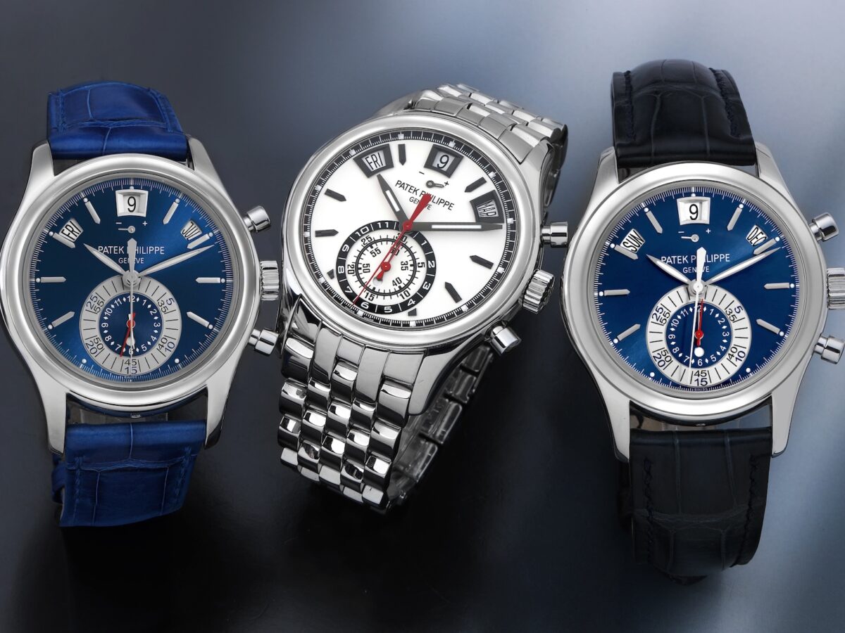 Three Patek Philippe Annual Calendar Chronograph Ref. 5960 watches arranged together. The center watch is the stainless steel Ref. 5960/1A with a white dial and steel bracelet, flanked by two platinum Ref. 5960P models with blue dials and blue alligator leather straps.