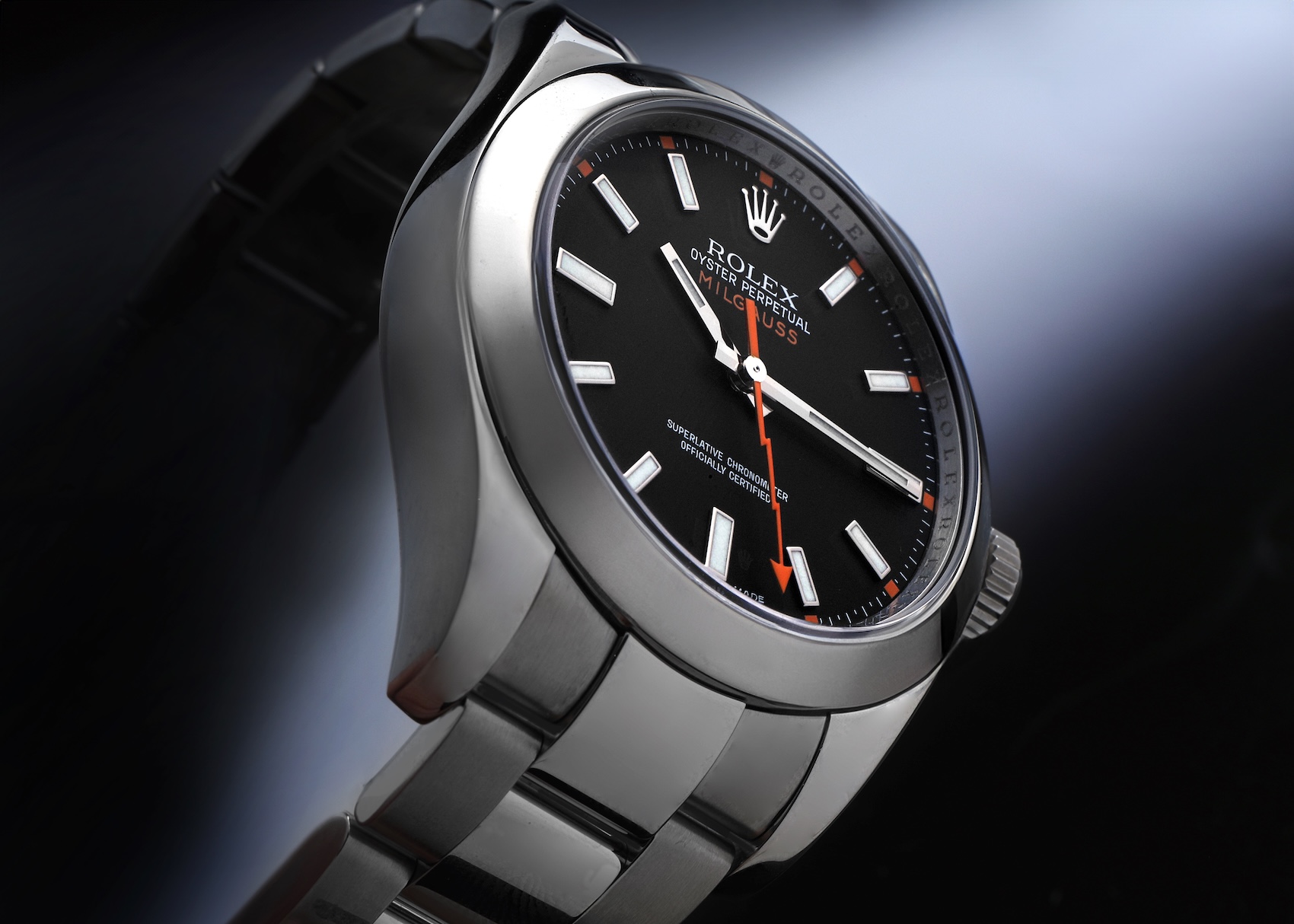 Rolex Milgauss 116400GV Anniversary model featuring a black dial, orange 3-6-9 markers, and green sapphire crystal.
