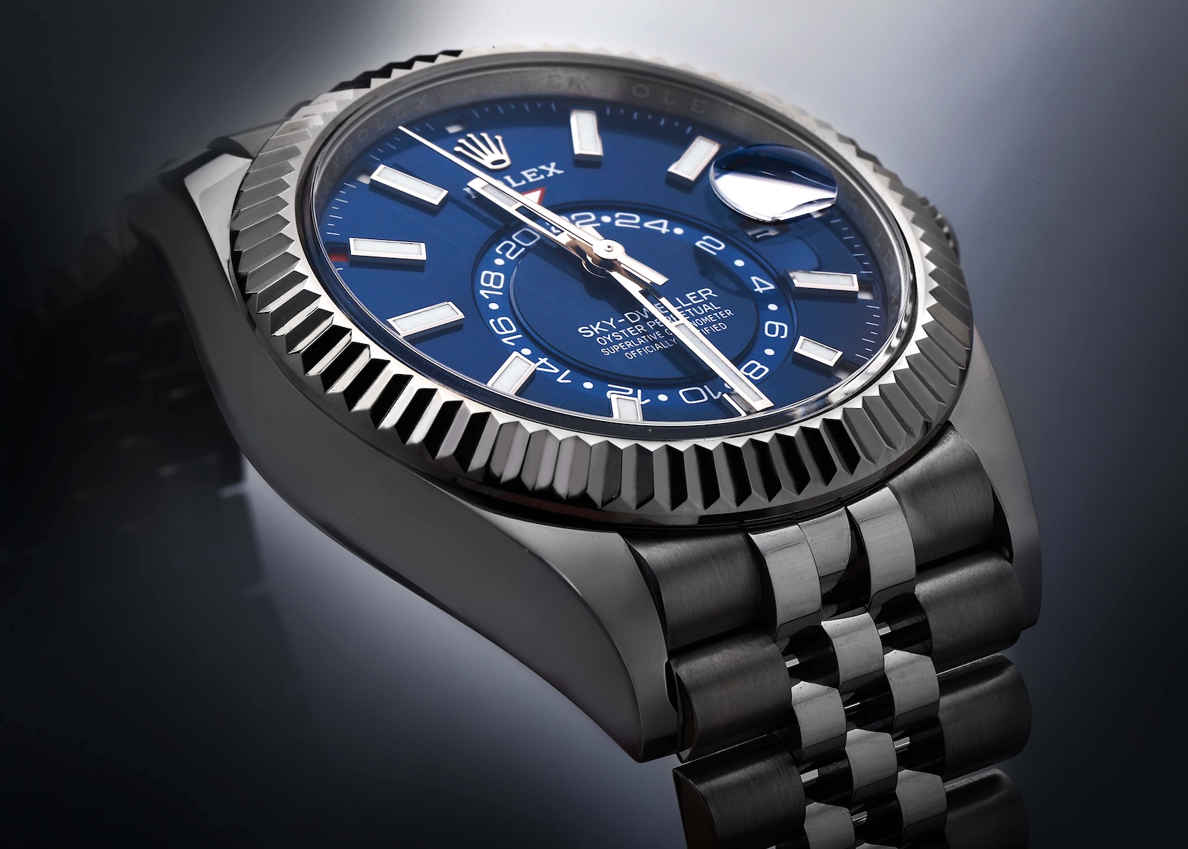 A close-up, low-angle shot of the Rolex Sky-Dweller ref. 336934 showing the fluted white gold bezel, blue dial, and the polished center links of the Jubilee bracelet.